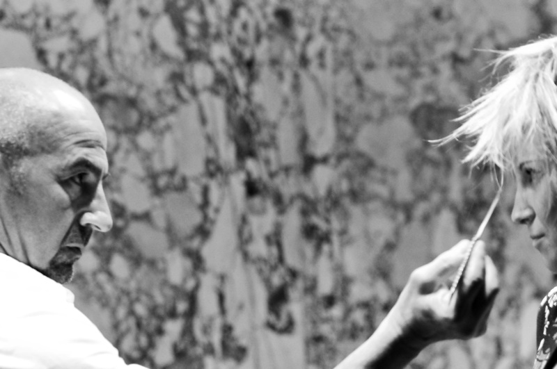 Black-and-white photo of a stylist trimming a model's hair backstage at the Ed Hardy fashion show at Mantra, Boston, 2009