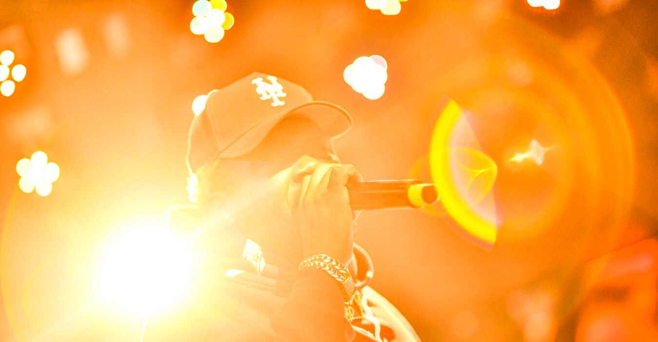 Dancehall artist Kranium performs at The Grand in Boston in 2026, microphone raised into orange stage light, photographed by Bobby Shakes